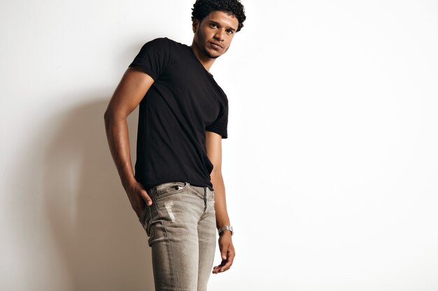 Low angle portrait of a sexy muscular African American young model in grey jeans and unlabeled black t-shirt isolated on white