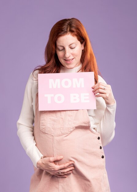 Low angle pregnant woman holding paper with mom to be message