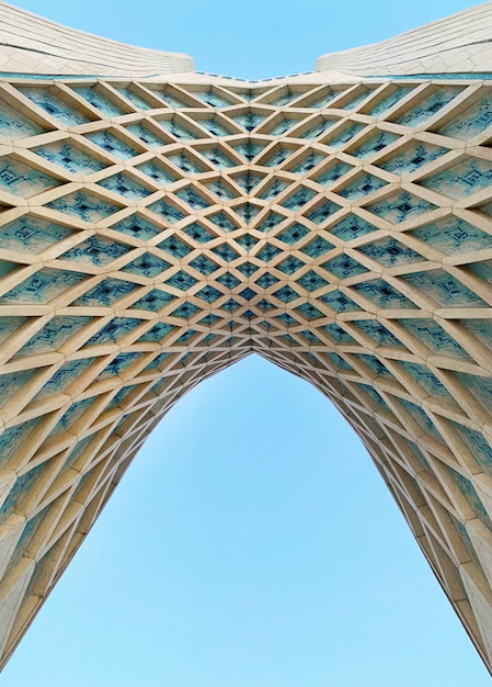 Free photo low angle shot of the arc of azadi tower in tehran with blue sky