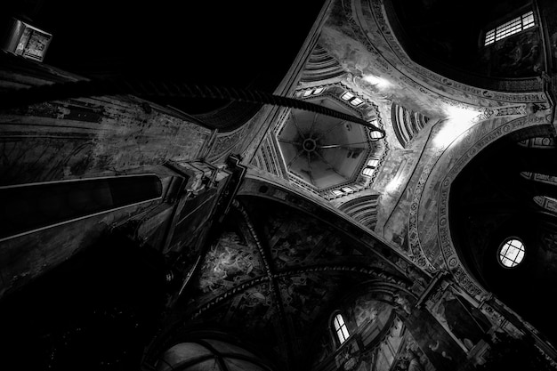 Low angle shot of an arched type ceiling with a rope hanging down in black and white