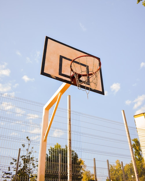 Low angle shot of a basketball ring with chain net against a blue cloudy sky