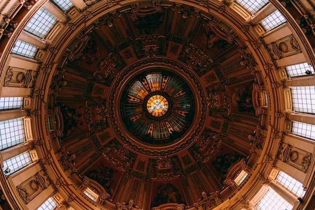 Free Photo low angle shot of the beautiful painting and windows on a ceiling in an old building