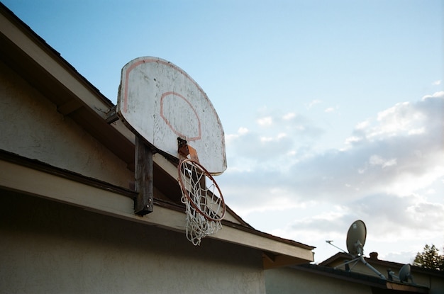 Free photo low angle shot of a broken basketball basket on the top of a house