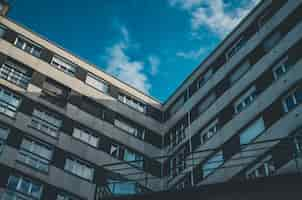 Free photo low angle shot of a brown and white  building with windows under a blue sky