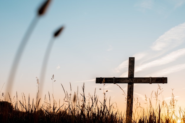 Low angle shot of a handmade wooden cross in a grassy field with a beautiful sky