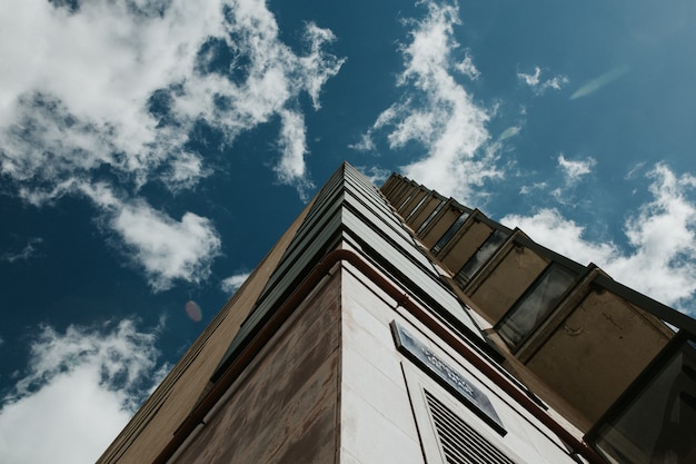 Free Photo low angle shot of a high-rise building under a clear blue sky with white clouds