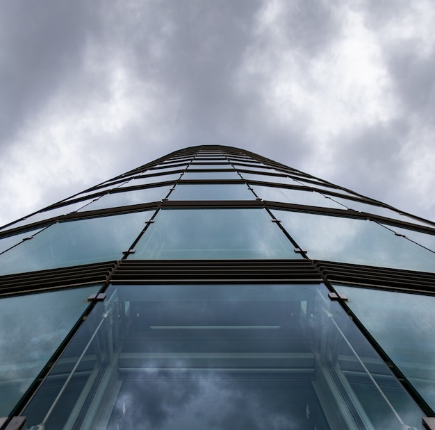 Free Photo low angle shot of a high rise building in a glass facade under the storm clouds