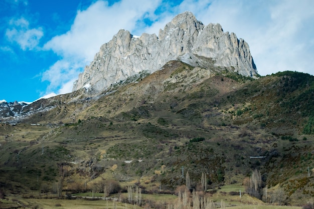 Low angle shot of a high rocky cliff on top of a mountain under a cloudy sky