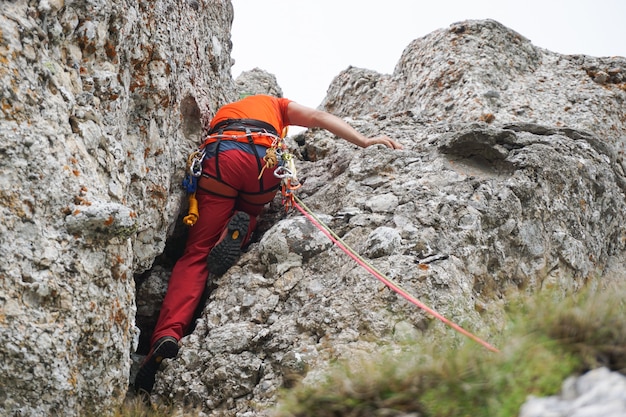 Free photo low angle shot of a male that is rope climbing a rocky cliff