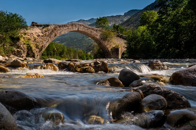 Low angle shot of an old arch bridge with a river under it during daylight