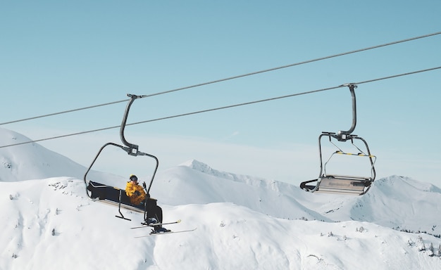 Free photo low angle shot of a person sitting on a cable car in a snowy mountain