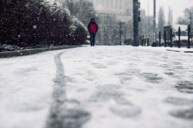 Low angle shot of a person walking on the snow covered sidewalk under the snow