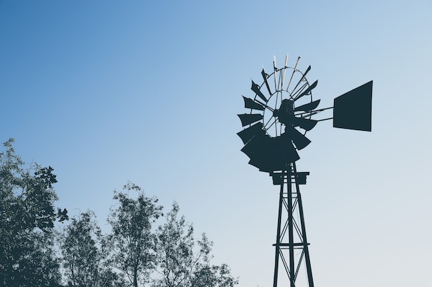 Free photo low angle shot of the silhouette of a windmill over the trees