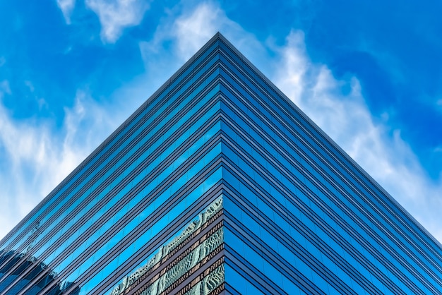 Low angle shot of a tall glass building under a blue cloudy sky