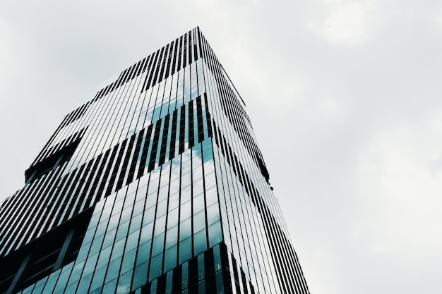 Free photo low angle shot of a tall high-rise modern business building with a clear sky