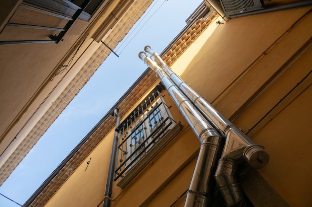 Low angle shot of two pipes as they go up the building next to a window