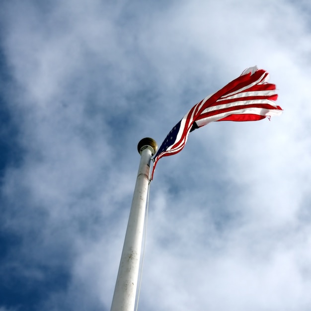 Free photo low angle shot of a united states flag with a cloudy blue sky