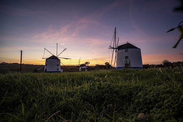 Free Photo low angle shot of windmills with a sunrise in a clear purple sky in the background