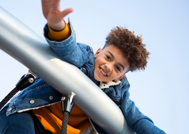 Free photo low angle smiley boy having fun at the playground