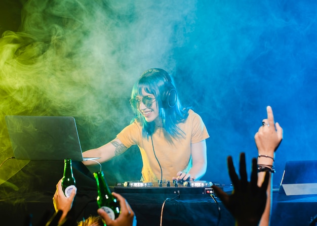 Low angle smiley female dj at mixing console