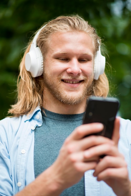 Free photo low angle of smiley man with smartphone and headphones