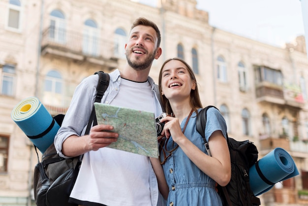 Free photo low angle of smiley tourist couple with map