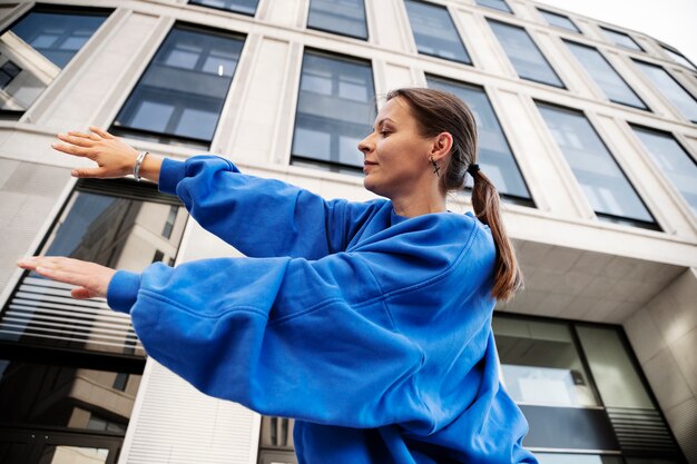 Low angle smiley woman dancing outdoors