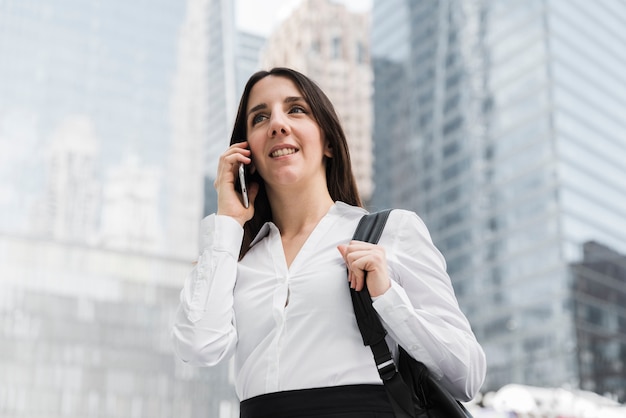 Low angle smiley woman talking on the phone