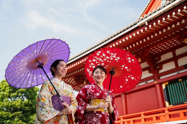 Low angle smiley women holding wagasa umbrella