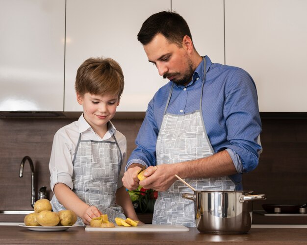 Low angle son assisting father while cooking