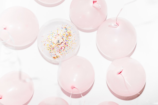 Free photo low angle view of birthday balloons with streamers on white backdrop