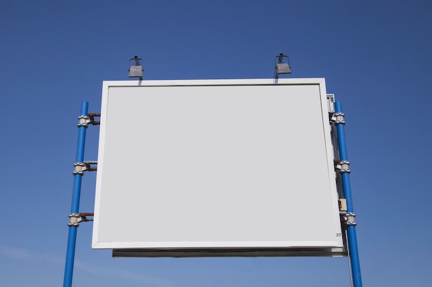 Free photo low angle view of blank hoarding with lights against blue sky