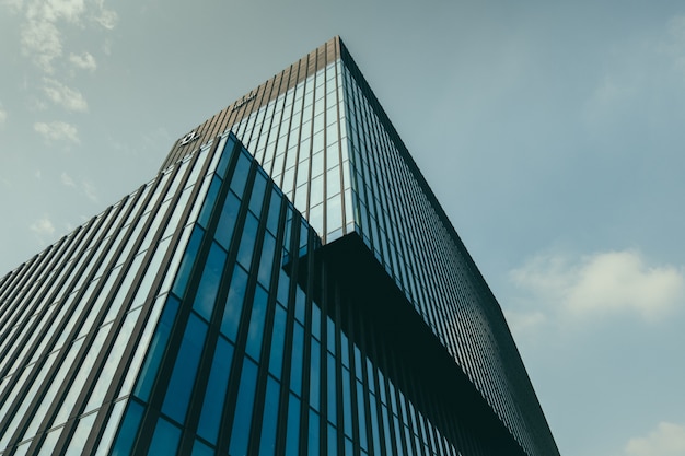 Low angle view of a building in a glass facade under the beautiful cloudy sky