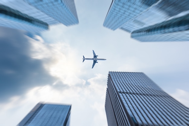 Free photo low angle view of business buildings with plane flying over