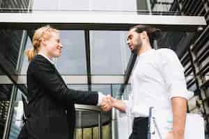 Free photo low angle view of businessman and businesswoman shaking each other hands