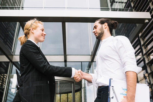 Free Photo low angle view of businessman and businesswoman shaking each other hands