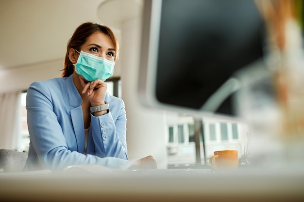 Low angle view of businesswoman with face mask working on desktop PC in the office