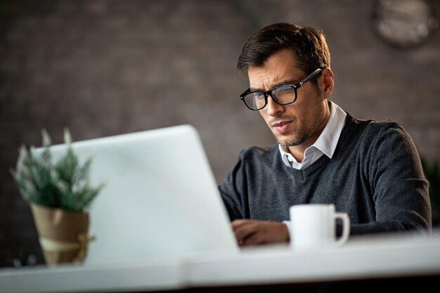 Low angle view of freelance worker using laptop and typing and email while being at work