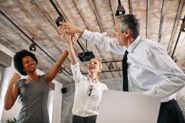 Free Photo low angle view of happy colleagues celebrating business success and having fun in the office