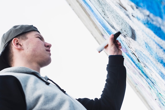 Free photo low angle view of a man drawing wall using marker