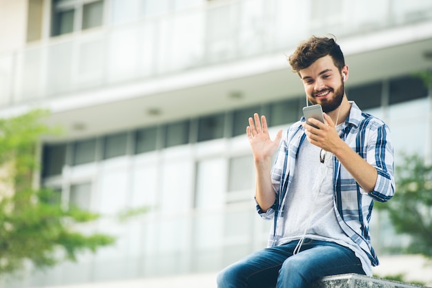 Low angle view of man videocalling to friend sitting in the university campus