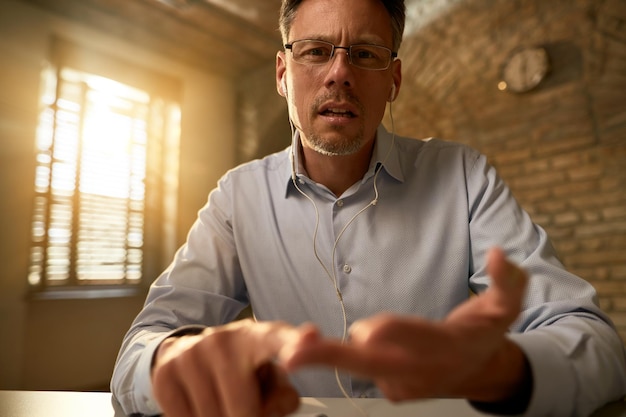 Low angle view of mid adult businessman gesturing while explaining something and looking at the camera in the office