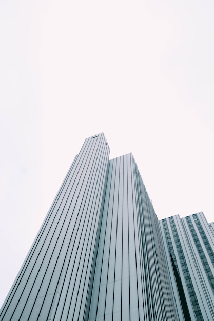 Free photo low angle view of a modern skyscraper with blue and white windows under a white sky