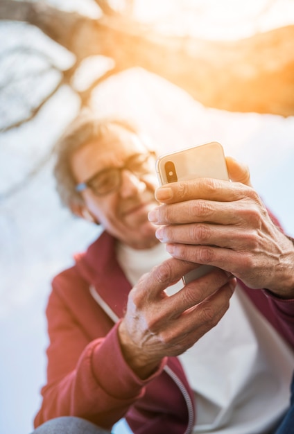 Low angle view of senior man using smart phone