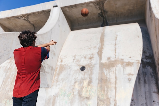 Free Photo low angle view of a teenage boy throwing basketball