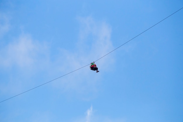 Free photo low angle view of tourist riding a zip line adventure against blue sky