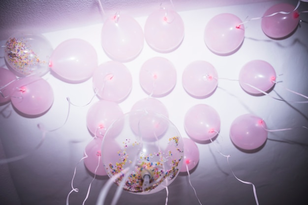 Free photo low angle view of white and pink balloons touching over the ceiling