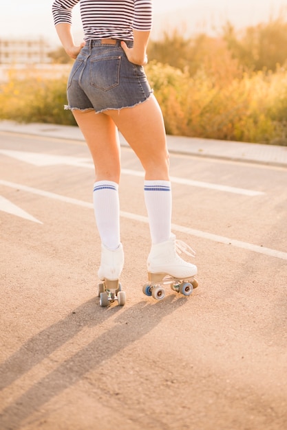 Low angle view of woman's leg wearing vintage roller skates standing on road