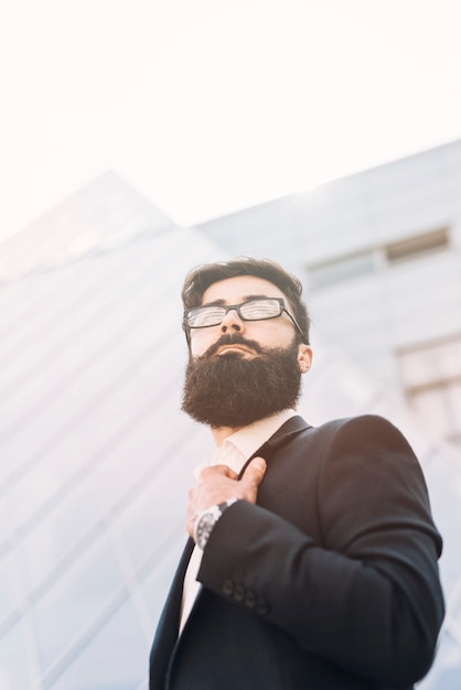 Low angle view of young businessman standing against corporate building