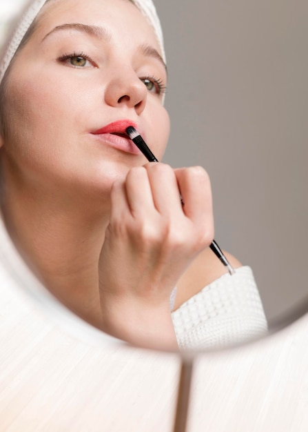 Low angle woman applying lipstick